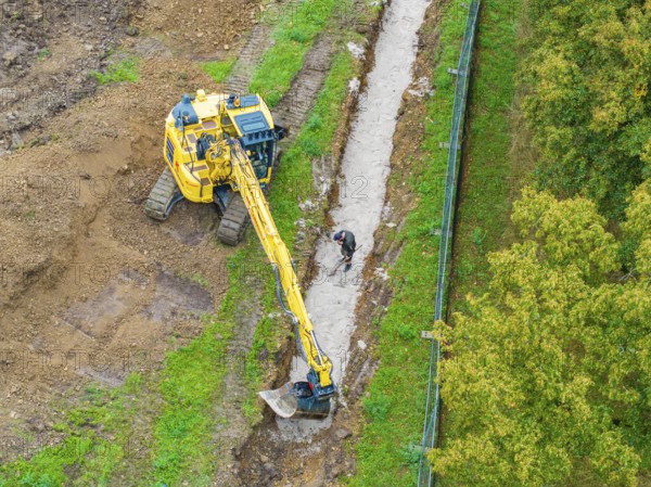 Excavator and construction worker at a ditch on a construction site, Bau PV Freifaechenanlage, Weil