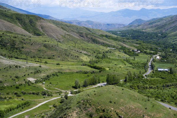 Green fields and rolling hills with roads leading through the area, under clear skies, countryside