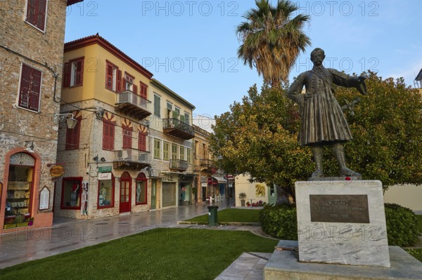 Old town of Nauplion, historical statue in a cozy street surrounded by old buildings and palm