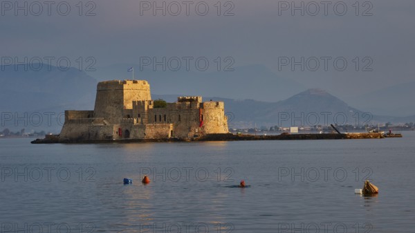 Bourtzi island fortress, old fortress on an island in the calm sea, surrounded by buoys and