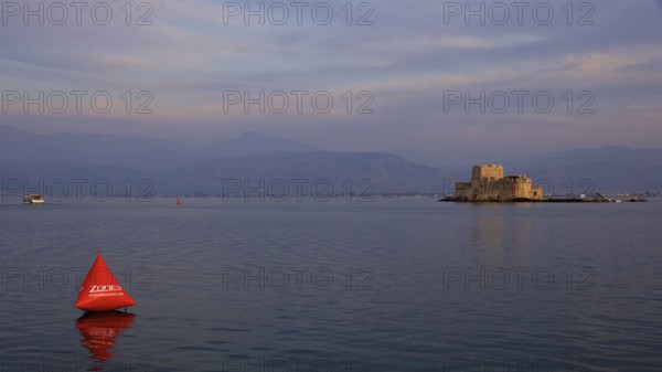 Bourtzi Island Fortress, A fortress in the sea at dusk with an orange buoy in calm water, Nauplion,