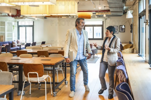 Diverse business professionals walking, talking, and discussing work in an open plan office,
