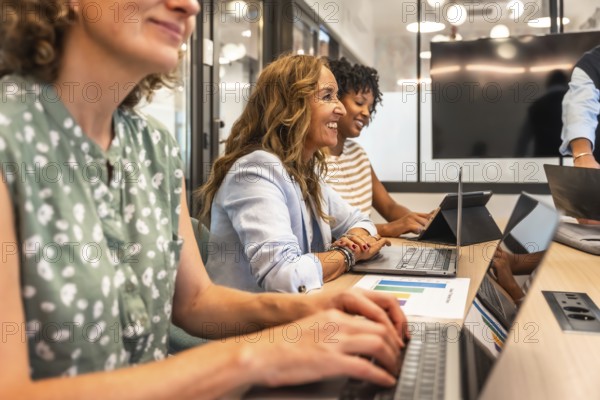 Diverse group of smiling businesswomen collaborating and engaging in productive work during a team
