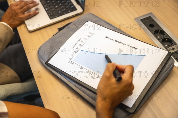 Business colleagues collaborating on strategy, analyzing a printout annual business growth chart