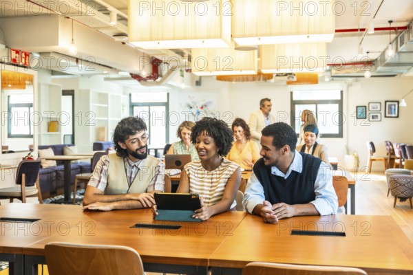 Diverse business colleagues collaborating around a tablet in a modern open plan office,