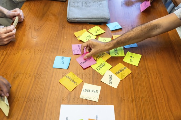 Business team gathered around wooden table arranging colorful sticky notes labeled planning.