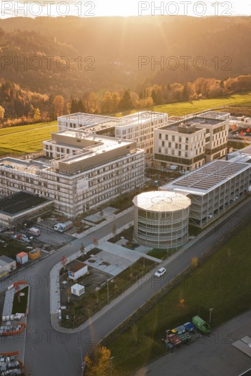 Modern buildings in rural landscape with forests and fields at sunset, aerial view, new hospital,