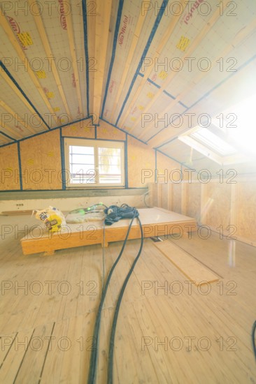 Renovation work in the attic with large windows and open insulation elements under the roof