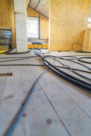 Construction site situation with scattered cables on a wooden floor. An incoming light source
