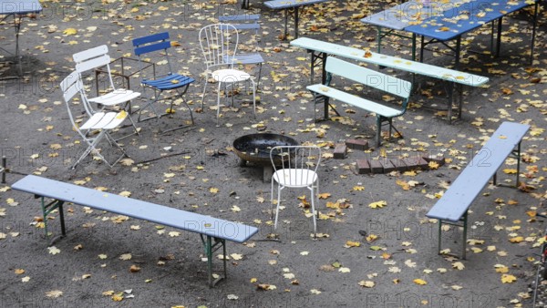 Chairs and tables stand unsorted around a fire bowl, a celebration in the garden is over, colorful