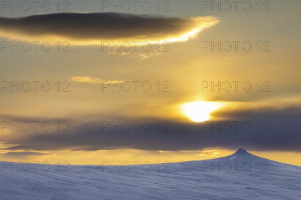 Midnight sun over snow covered mountain in Arctic landscape at Mohnbukta, bay at western shore of