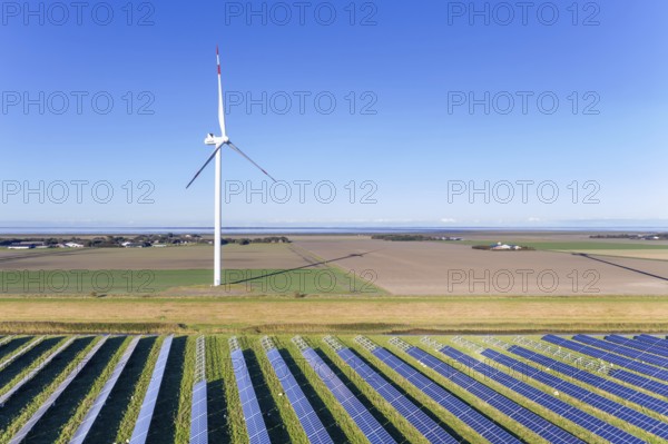 Aerial view over hybrid power plant combing solar photovoltaic modules and wind turbines, North