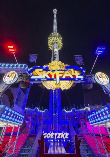 Colourfully illuminated Skyfal free fall tower at night at the All Saints Fair, Soest, North