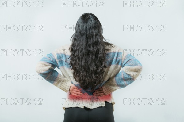 Suffering young woman with pain holding his back isolated. Female with spine problems isolated.