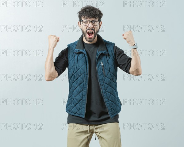 Excited young man celebrating looking at camera raising arms isolated. Happy guy with sunglass