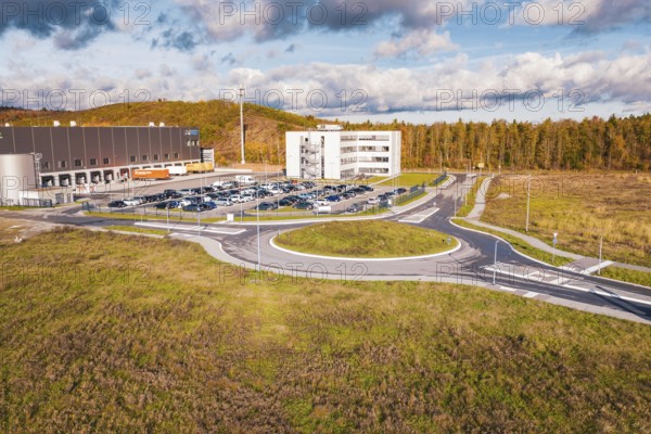 Building complex and roundabout in autumn landscape under blue sky, new Lindenrain industrial park,
