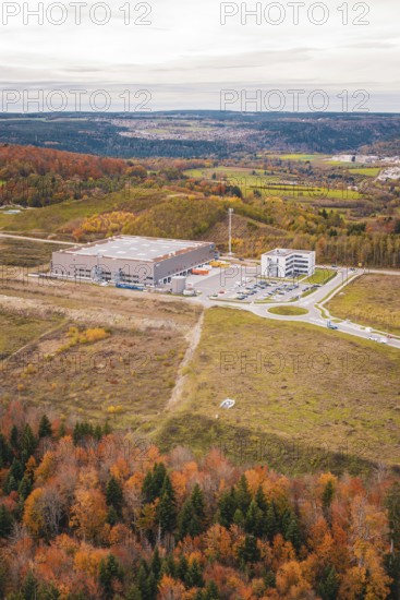 Large warehouse in the middle of a hilly landscape with autumn trees, new Lindenrain industrial