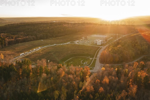 Sunset over a building in an autumn forest area with golden lighting, new Lindenrain industrial