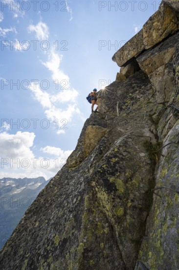 Female mountaineer on steep rock face on the secured via ferrata Krokodil-Bergsee am