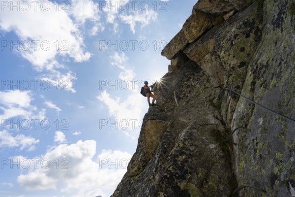 Female mountaineer on steep rock face on the secured via ferrata Krokodil-Bergsee am