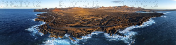 Coast with lava fields, volcanic landscape near Los Hervideros with red volcano Montaña Bermeja, in