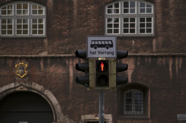 Traffic light for pedestrians, pedestrian traffic light is on red, bus traffic sign has priority,