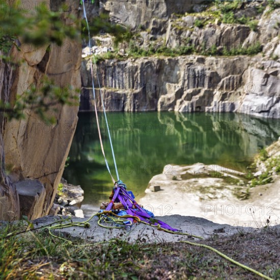Ropes, slings and carabiners secured on a rock edge, opal lake in the granite quarry, Moselleøkken