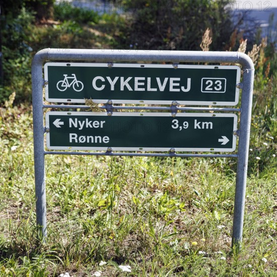Danish sign with the inscription Radweg 23, distance to Nyker and Rønne, bicycle tour through