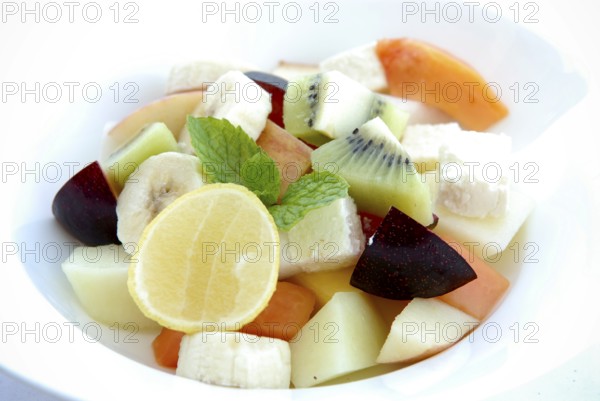 Fresh fruit salad with lemon, banana, papaya, kiwi, plums, melon and mint leaves in a bowl, Palace