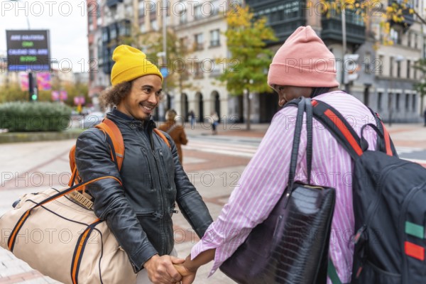 Multiethnic gay couple holding hands, beanies and backpacks, smiling as they walk through a vibrant