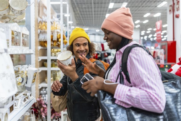 Happy couple smiling and browsing home decor in a modern store, examining a decorative item while