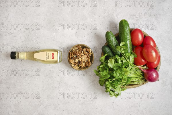A colorful arrangement of fresh tomatoes, cucumbers, and herbs on a light gray surface. A bowl of