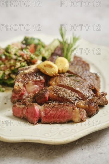 Juicy grilled steak rests on a decorative plate, served alongside a fresh salad made with vibrant