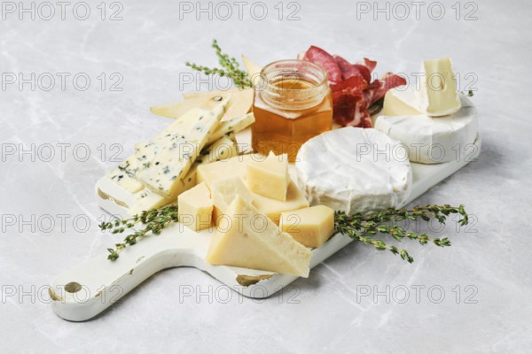 A beautiful spread featuring various types of cheese, honey in a jar, and slices of cured meat on a