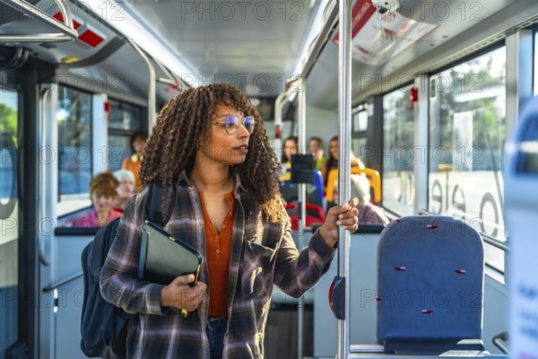 Young woman with curly hair and glasses stands inside a city bus holding a pole, wearing a backpack