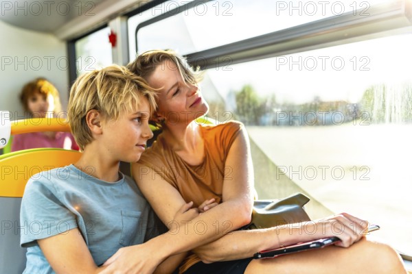 Mother and son relaxing and enjoying the warm sunlight streaming through the window while traveling