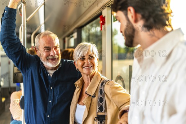 Happy senior couple chatting with a young man while riding a modern city bus, smiling and enjoying