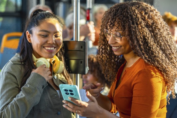 Two smiling multiethnic women bonding and sharing content on a smartphone while commuting together