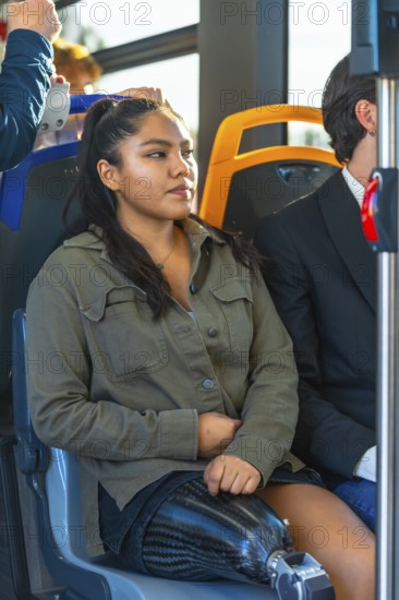 Young woman with a carbon fiber prosthetic leg sitting on public transport, riding a modern bus,