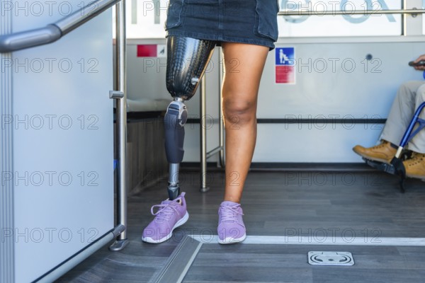 Amputee woman with a prosthetic leg and sneakers standing inside a bus, sharing the accessible