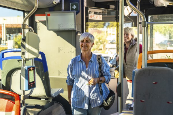Smiling senior woman standing in a modern public transport bus, enjoying her journey and commuting