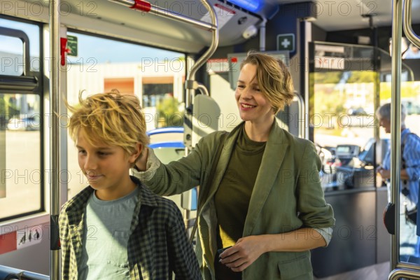Mother and son share a warm moment on a modern city bus, woman resting her hand on his shoulder as