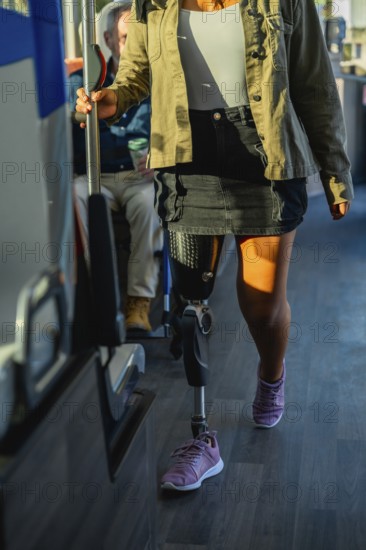 Woman with prosthetic leg and athletic shoe standing on a city bus, holding the handrail while