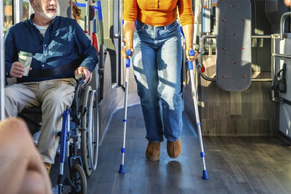 Senior man in wheelchair and woman with crutches navigate a busy city bus aisle together,