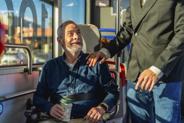 Young caregiver places hand on shoulder of smiling senior man in wheelchair during accessible
