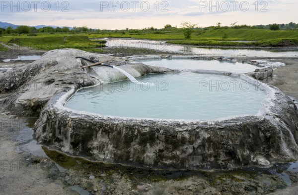 Hot spring pool in natural landscape with vast meadows and cloudy sky, springs of Amaghleba,