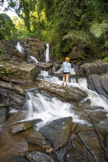 Tourist at Derema Waterfall, flows through dense vegetation, tropical rainforest in Amani Nature