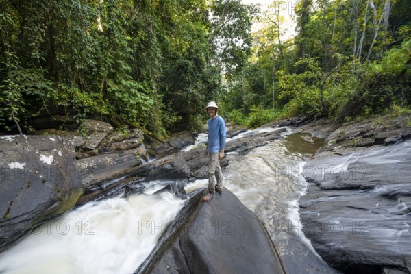 Tourist at Derema Waterfall flows through dense vegetation, tropical rainforest in Amani Nature
