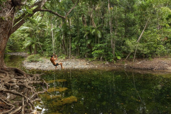 Man swings on a rope in the swimming pool at Emmagen Creek in Daintree National Park, Cape