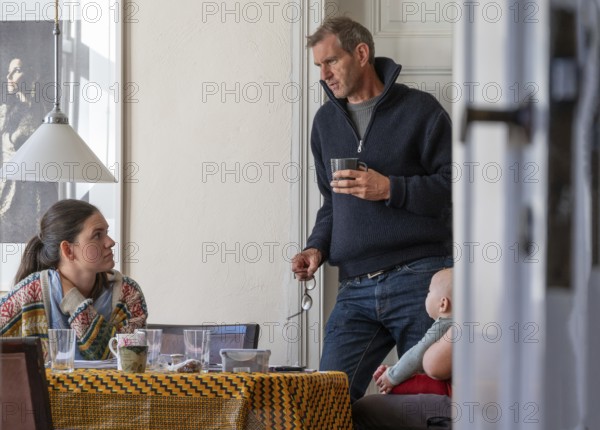 Home office, father and daughter working at the breakfast table, grandchild on the right,
